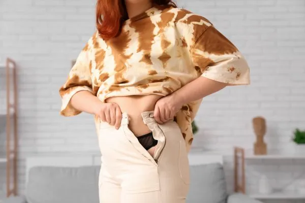 Image of woman trying to do her trousers up after pregnancy weight gain Blackheath