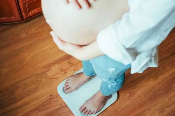 Image of woman weighing herself and experiencing weight gain through pregnancy Blackheath